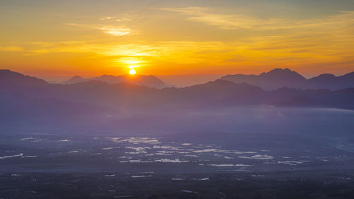 Scenic view of silhouette mountains against orange sky