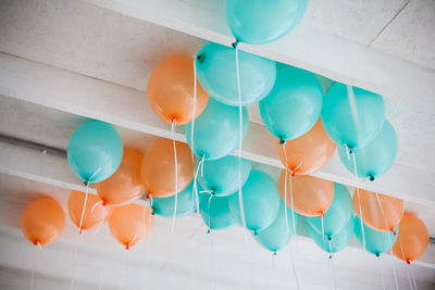 Orange and green balloons with white ribbons on the ceiling