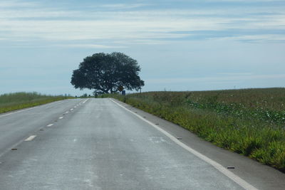 Road amidst field against sky