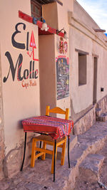 Empty chairs and table against wall