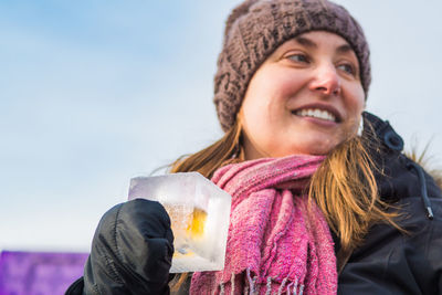 Portrait of smiling young woman against sky during winter