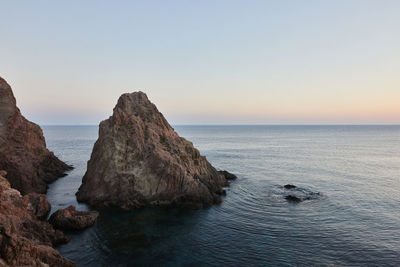 Scenic view of rock formation in sea against clear sky