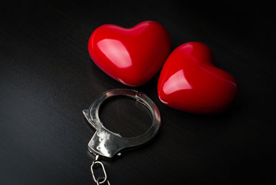 Close-up of heart shapes and handcuffs on black background