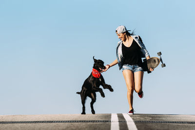 Low section of woman with dog against clear sky