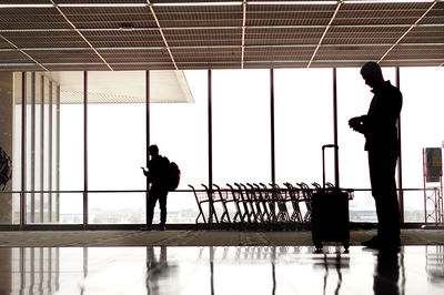 Silhouette man standing by window at airport