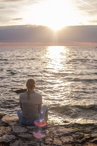 Back view of woman sitting by the sea