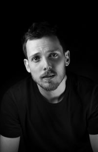 Portrait of young man against black background