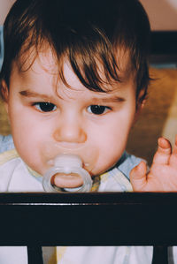 Close-up portrait of cute baby boy sucking pacifier at home