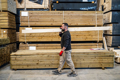 Worker carrying wooden plank at warehouse