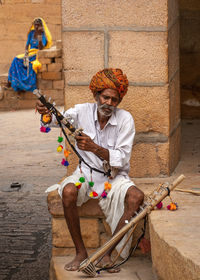 Full length of man sitting on wall