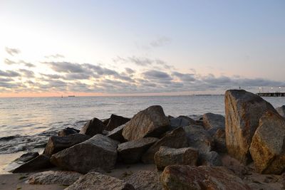Rocks on sea shore against sky during sunset