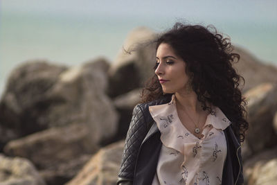 Young woman looking away while rock on land