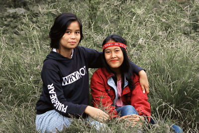 Portrait of a smiling young woman sitting on field