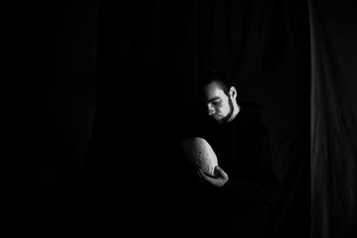 Portrait of young man looking away against black background