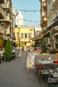 Chairs and tables at sidewalk cafe by buildings in city