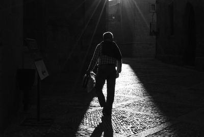 Rear view of man walking on footpath at night