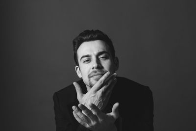 Portrait of young man standing against black background