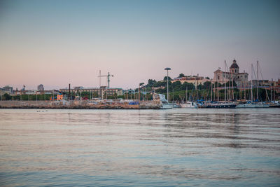 Sailboats in marina at harbor against clear sky