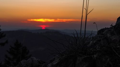 Scenic view of silhouette rocks against romantic sky at sunset