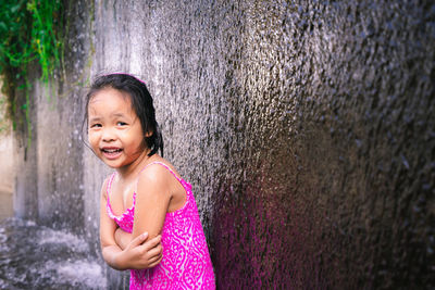 Portrait of girl standing against waterfall