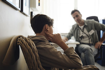 Male student explaining while talking with school nurse in office