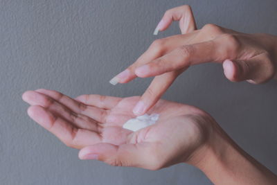 Close-up of hand applying cream against wall