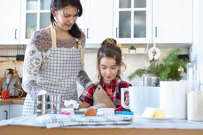 Mother and daughter sitting on table at home