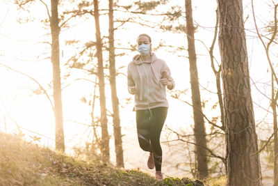 Full length of woman wearing mask exercising at park