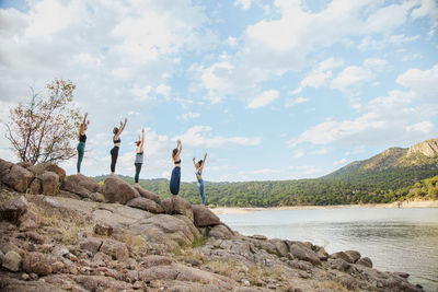 People on rock by sea against sky