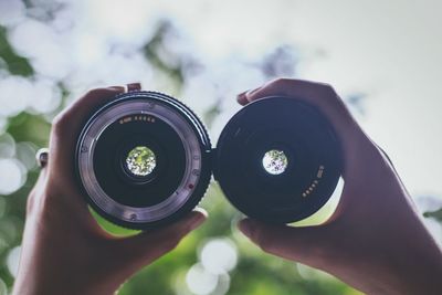 Cropped hand holding camera lenses