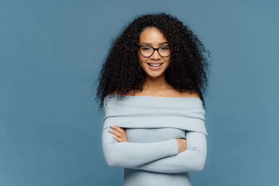 Portrait of a smiling young woman against blue background