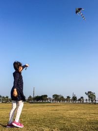 Full length of child playing with umbrella against clear blue sky