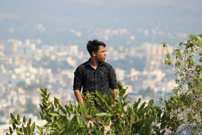 Young man looking away against plants