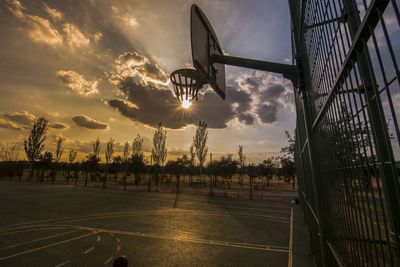 Silhouette basketball hoop on street against sky during sunset