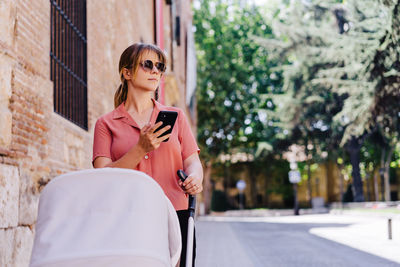 Young woman using mobile phone while sitting outdoors