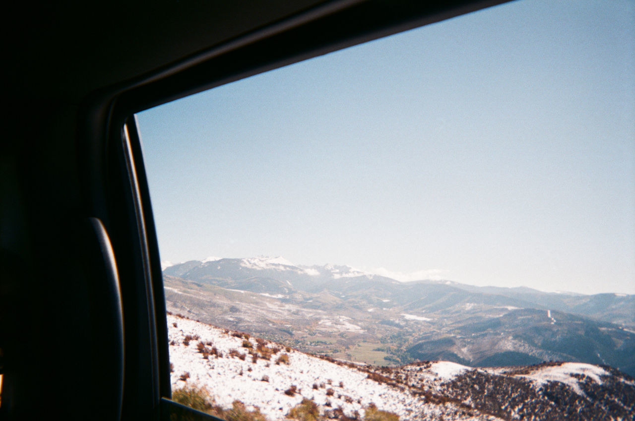 SCENIC VIEW OF MOUNTAINS AGAINST CLEAR SKY SEEN FROM WINDOW