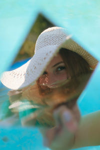 Close-up of young woman holding mirror with reflection in wading pool