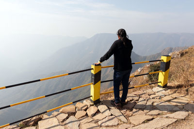 Full length of man standing on railing against mountain