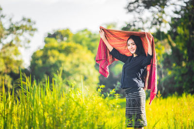 Portrait of happy young woman wearing shawl amidst grassy field