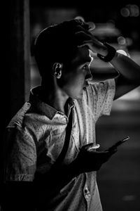 Side view of young man using mobile phone