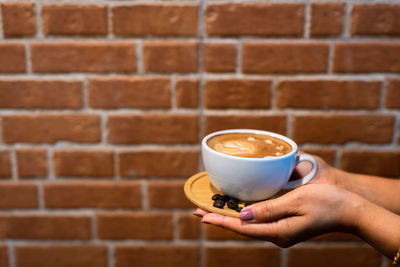 Coffee cup on table against brick wall