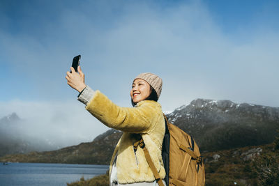 Low angle view of woman taking selfie against sky