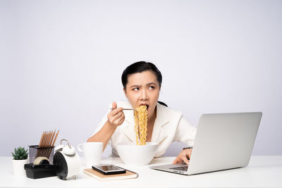 Young woman using laptop on table against white background