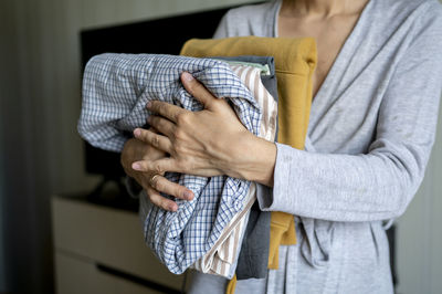 Woman holding ironed folded clothes at home