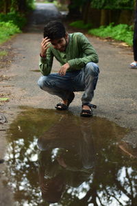 Full length of man crouching by puddle