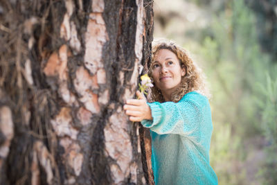 Portrait of a smiling young woman against tree trunk