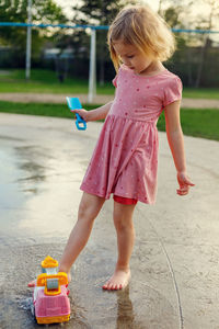 Small child at playground in public park playing with toys and water. girl at splash pad in summer