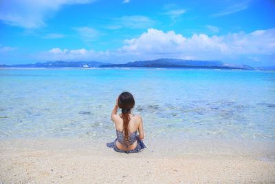 Rear view of shirtless man looking at sea against sky
