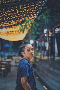 Man looking away while standing on street in city