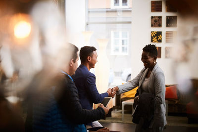 Smiling businessman shaking hands with female entrepreneur in office seminar